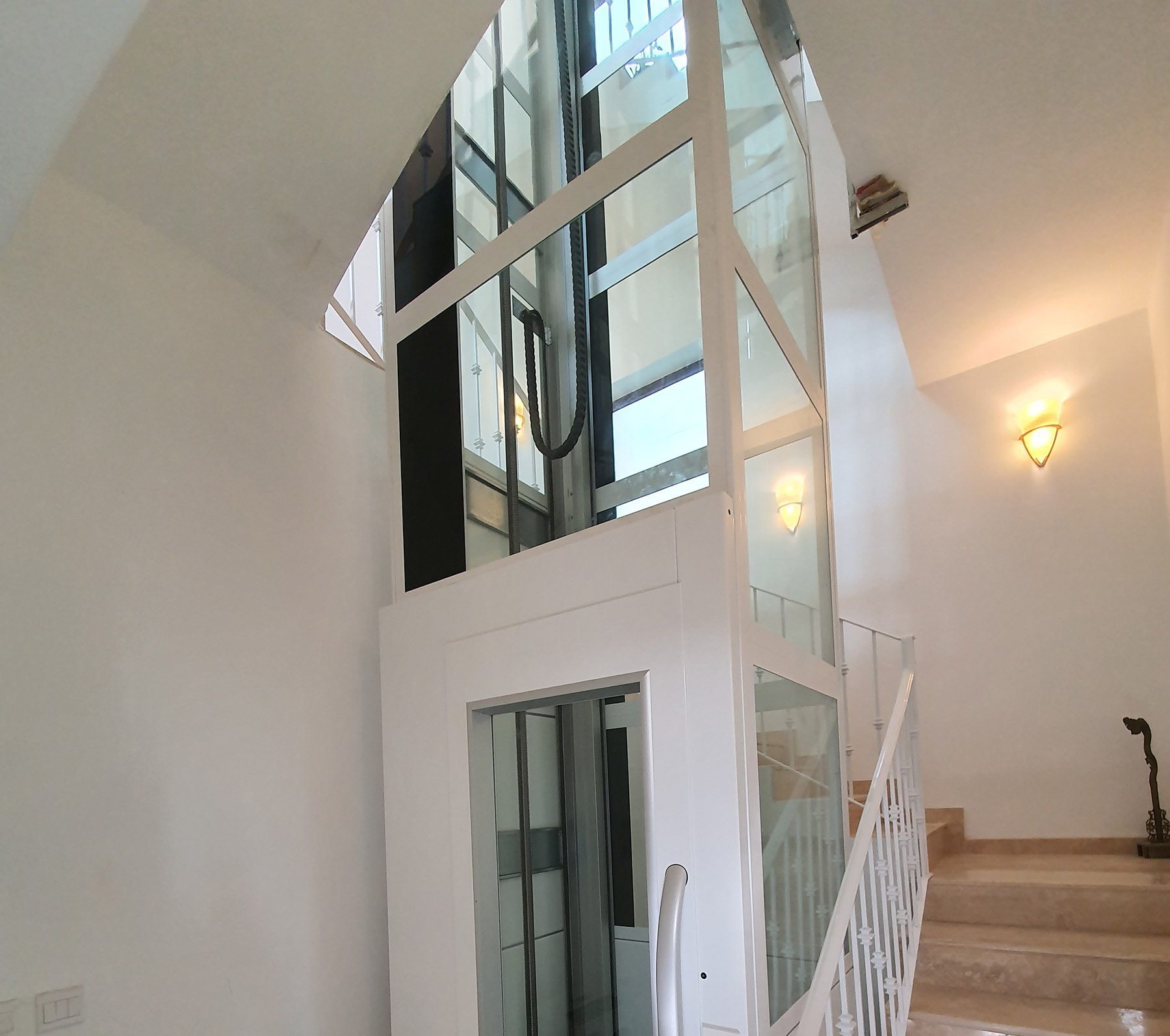 A photo of the Cibes Lift in white, installed in a traditional Maltese home and fitted in the centre of a spiral staircase.